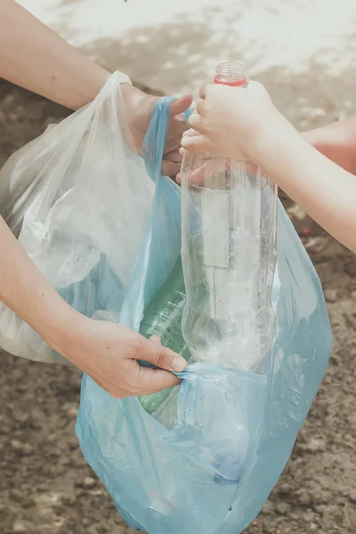 Mãe e filho coletando garrafas de plástico. A família leva o saco do lixo. Poluição plástica em terra . — Fotografia de Stock