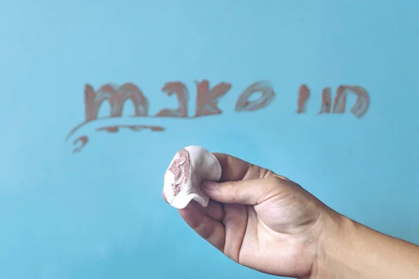 La mano femenina limpiando el lápiz labial hecho palabra maquillaje con tampón blanco — Foto de Stock
