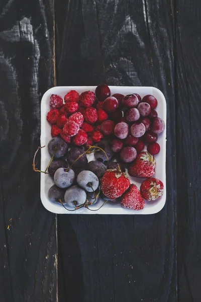 自家製の新鮮な冷凍フルーツ。暗い素朴な木に健康的な甘いデザート.  — 無料ストックフォト