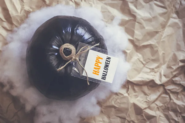 A big black pumpkin with an empty white paper tag — Free Stock Photo