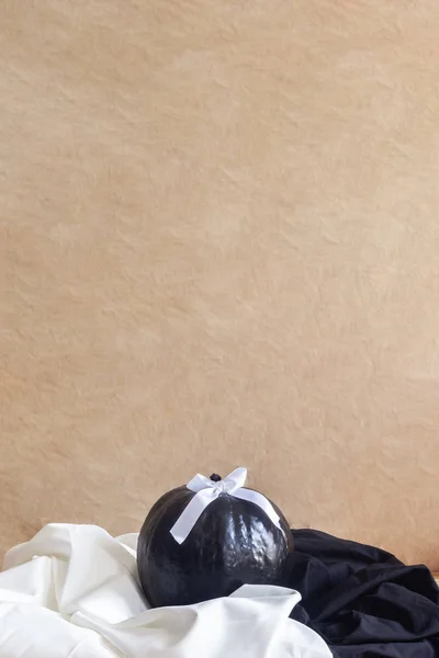 Μεγάλη αποκριάτικη κολοκύθα διακοσμημένη με κορδέλα σε μαύρο και άσπρο ύφασμα φόντου — Φωτογραφία Αρχείου