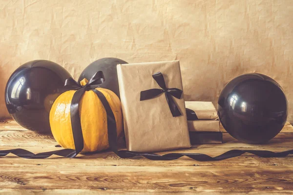 Celebrando Halloween. Calabazas naranjas y negras con caja de regalo decorada y globos aéreos — Foto de stock gratuita