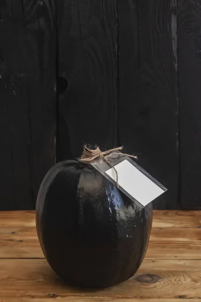 A big black pumpkin with an empty white paper tag