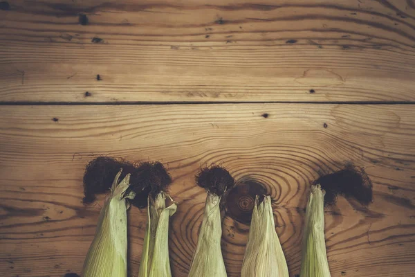 Baru jagung tongkol mentah pada latar belakang kayu. Jagung mentah dengan kulit — Stok Foto