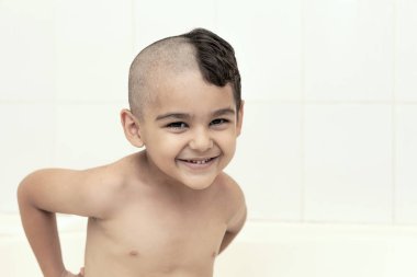 Six-year boy at haircutting at home. Father cut half of the son's hair off at the bathroom clipart