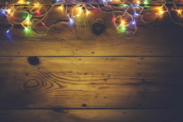 Christmas decorative lights. Christmas garland lights on wood. Colorful Xmas light bulbs on rustic brown plank