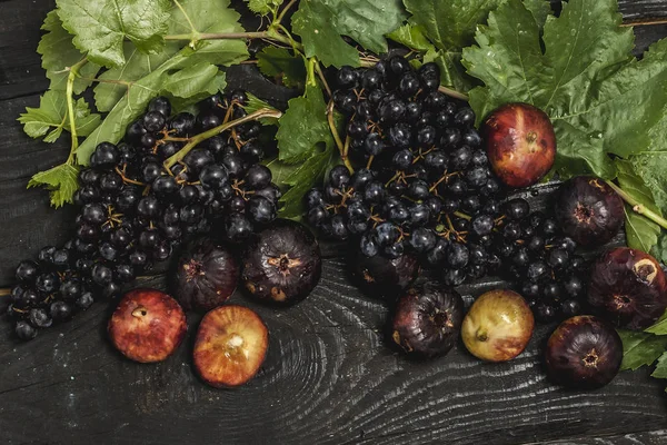 Buah-buahan segar dipetik di musim gugur. Anggur hitam dan ara di atas meja kayu yang gelap — Stok Foto