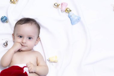 Noel Baba şapkalı 9 aylık erkek bebek. Noel sabahı. Küçük çocuk oynuyor.