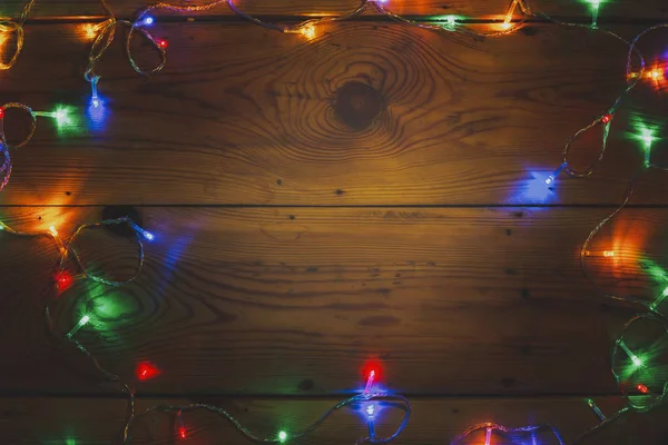 Christmas decorative lights. Christmas garland lights on wood. Colorful Xmas light bulbs on rustic brown plank — Stock Photo, Image