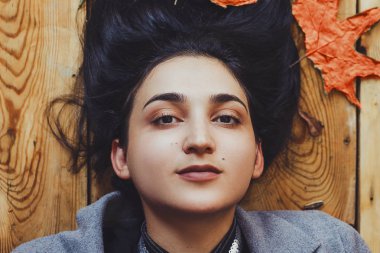 Sonbahar kadını. Sonbahar sezonu konsepti. Tahta zeminde yatan bir kadın portresi. Üstte görüntü