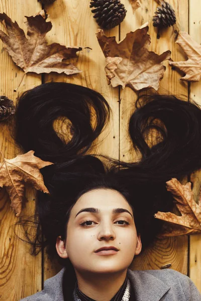 秋天的女人秋季概念。躺在木地板上的女人的画像。顶部视图 — 图库照片