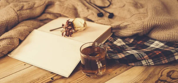Fall background. Compoziția de toamnă cu ceai fierbinte, carte, floare de trandafir uscată și pulover tricotat. O ceașcă de ceai fierbinte, eșarfă tricotată pe masă de lemn . — Fotografie, imagine de stoc