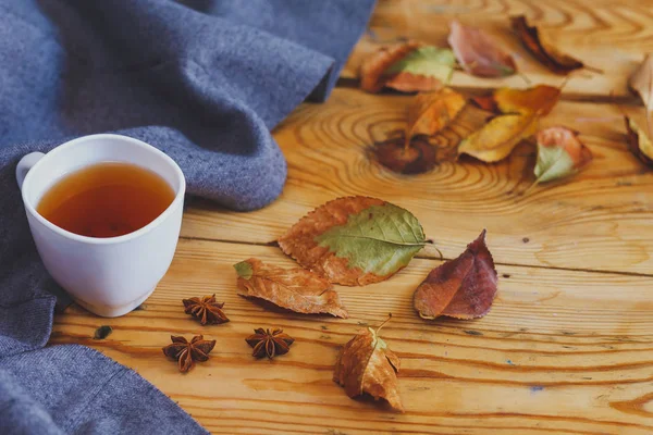 Soğuk sonbahar günleri. Tahta masanın üzerinde sonbahar yaprakları olan bir fincan çay. Ahşap bir masada Çay Isınma — Stok fotoğraf