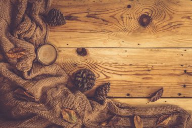 Sonbahar arka planı. Ahşap masa üzerinde bir fincan sıcak kahve, örme atkı ve kozalaklı çörekler. Sonbahar kahvesi. Üst te. Kopyalama alanı