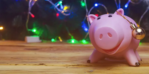 Slavnostní finance. Prasátko banka a vánoční hračky proti zdobené vánoční stromeček. Koncept vánočních financí. — Stock fotografie