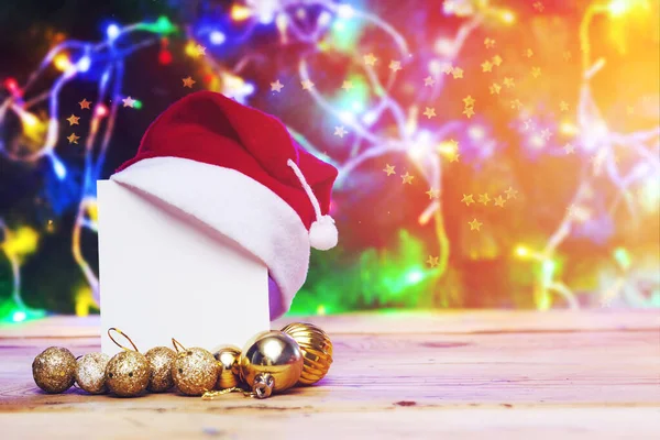 圣诞树装饰和礼品盒,桌上有一张空白卡片. 圣诞树上挂着空白纸的圣诞玩具，灯亮着。 假日装饰。 圣诞节背景 — 图库照片