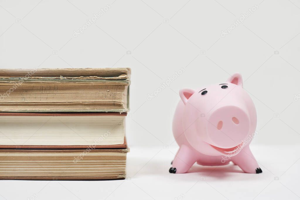 Stack of old books with piggy bank. Cost of education. Saving money for college. Save and pay for child college education