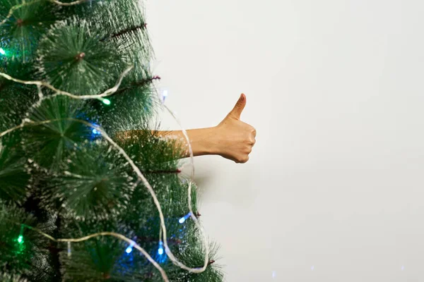 Thumbs-up χειρονομία πίσω από το δέντρο Χριστούγεννα — Φωτογραφία Αρχείου