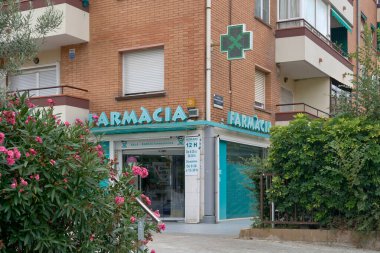 Viladecanlar. Barselona - 2 Eylül 2025: Parlak ışıklı yeşil bir haç, İspanyol kentsel ortamındaki yerel bir eczaneyi tanımlayan bir konut binasının köşesinde duruyor..