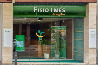 Viladecanlar. Barcelona - 02 Eylül 2025: Viladecan, Katalonya 'daki Fisio i Mes kliniğinin mağazası. Görüntü yeşil işareti ve büyük cam giriş kapılarını gösteriyor..