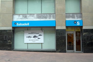 Viladecanlar, Barcelona - 2 Eylül 2025: Pencerede mali hizmetleri destekleyen büyük bir poster bulunan Sabadell banka şubesinin cephesi.