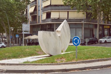 Viladecanlar. Barselona - 05 Eylül 2025: Viladecan 'daki günlük yaşamın resmi. Apartman binaları ve ağaçların önündeki trafiği düzenleyen modern bir halka açık sanat eserine sahip döner kavşak.