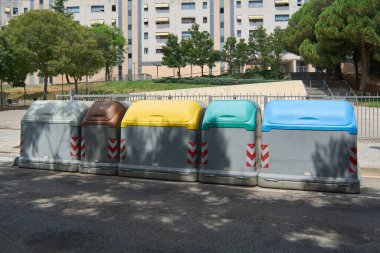 Viladecanlar. Barcelona - Eylül 2025: İspanya 'da atıkların doğru sınıflandırılması için renkli kapaklı konteynırlar (mavi, yeşil, sarı, kahverengi, gri) sırası.