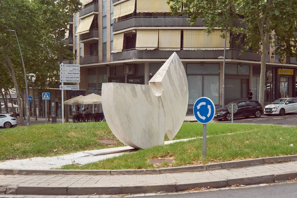 Viladecanlar. Barselona - 05 Eylül 2025: Viladecan 'daki günlük yaşamın resmi. Apartman binaları ve ağaçların önündeki trafiği düzenleyen modern bir halka açık sanat eserine sahip döner kavşak.