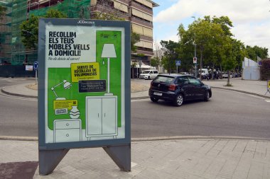 Viladecanlar. Barcelona - 06 de septiembre, 2025: Büyük çaplı bir atık toplama servisi reklamı JCDecaux tabelasında bir minibüs ve arka planda bir bina ile görülebilir.
