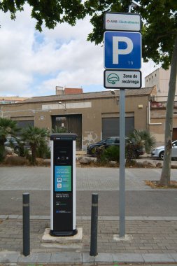 Viladecanlar, Barcelona - 17 Eylül 2025: Görüntü, sürdürülebilir hareketlilik temaları için ideal bir kentsel park alanındaki elektrik yükleme noktasını gösteriyor.