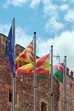 Viladecanlar. Barselona - 18 Eylül 2025: Torre del Baro 'nun tarihi cephesinde sallanan bayrakların yakın çekimi.