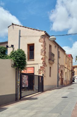 Viladecanlar. Barcelona - 18 Eylül 2025: Güneşli bir öğleden sonra Katalan mimarisinin eşsiz karakterini çıplak taş duvarları ve modern demir bir kapısı olan eski bir evle yakalamak.