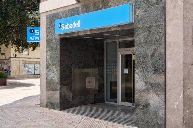 Viladecanlar. Barcelona - 18 Eylül 2025: Banc Sabadell ATM 'ye girişin modern bir şehirde mevcut olan kentsel mimari ve bankacılık hizmetlerini ön plana çıkaran bir editoryal çekimi.