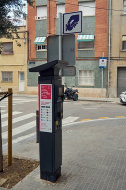 Viladecanlar. Barcelona - 18 Eylül 2025: Kentsel sokak köşesinde şehir yönetimi temaları ve kentsel hizmetler için ödeme temaları temsil eden modern bir parkmetreye yakın çekim.