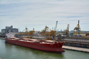 Venedik. İtalya - 22 Eylül 2025: Kırmızı gövdeli taşıyıcı gemi, AthingA II, kenetlendi ve endüstriyel bir terminalde gantry vinçleri ile hizmet vermektedir..