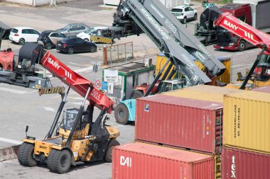 Venezia 'da. İtalya - 23 Eylül 2025: Sany ve Konecranes Erişicileri, karmaşık uluslararası taşımacılık ve ticaret lojistiğini gösteren limandaki çeşitli nakliye konteynerleri arasında faaliyet göstermektedirler..