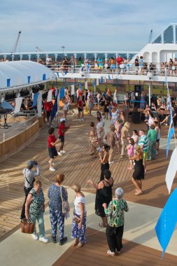 Venedik. İtalya - 23 Eylül 2025: Çeşitli yaşlardaki insanlar bir yolcu gemisinin ahşap güvertesinde dans ediyor ve sosyalleşiyorlar. Atmosfer şenlikli ve tatil gibi..