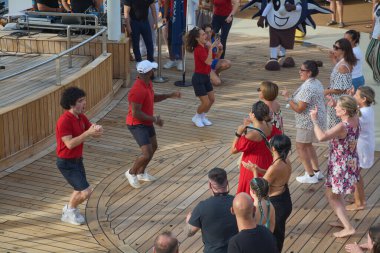 Venedik. İtalya - 23 Eylül 2025: Canlı bir turist grubu, geminin eğlence dersinin bir parçası olarak bir açık hava dans dersine katılırken gülümseyip alkışlıyor.