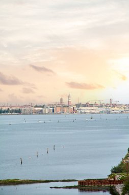 Venedik, İtalya 'nın ikonik ufuk çizgisi, St. Mark' s Campanile, gölün üzerinde sıcak, parlayan bir ışık ile güzel bir günbatımı gökyüzüne karşı siluet.