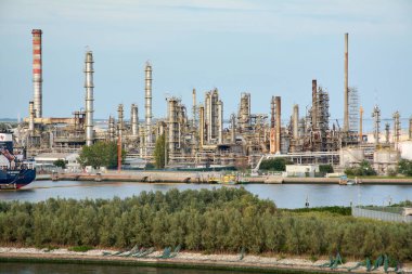 Venedik. İtalya - 24 Eylül 2025: Çok sayıda kulesi, borusu ve bacası bulunan genişleyen bir petrol rafinerisi ve petrokimya fabrikası sanayi limanı bölgesindeki limana hakim durumda.