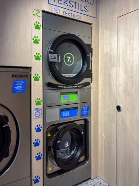 Riga, Letonya - Eylül 04, 2025: Evcil hayvan tekstili için Speed Queen makineleri ile donatılmış çağdaş çamaşır odası, parlak ve hoş geldin tasarımı içeriyor