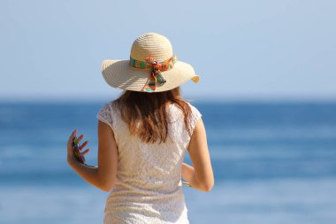 Sahilde şapka ve cep telefonu ile kız