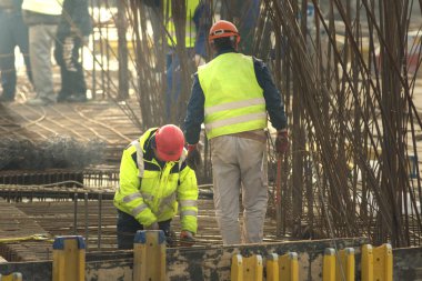 İki İşçi çerçeve güçlendiriciler içine metal çubuklar çubukları örme