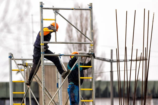 Dos trabajadores construyen andamios metálicos en obra — Foto de Stock