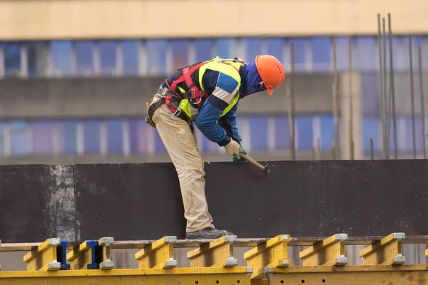 Trabajador golpea clavos en el sitio de construcción — Foto de Stock