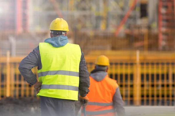 Dois trabalhadores em amarelo e laranja no canteiro de obras — Fotografia de Stock