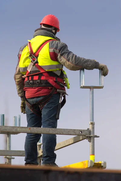 Trabajador con cinturón de seguridad y casco rojo en obra sobre — Foto de Stock