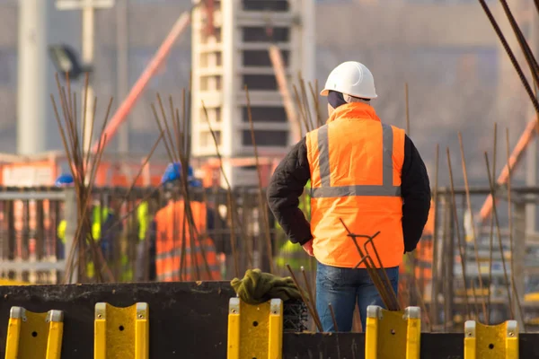 Supervisor em capacete laranja e branco no local de construção — Fotografia de Stock