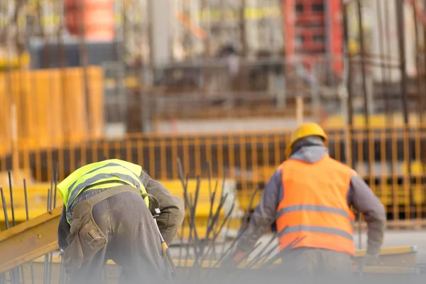 Dois construtores em amarelo e laranja no canteiro de obras — Fotografia de Stock