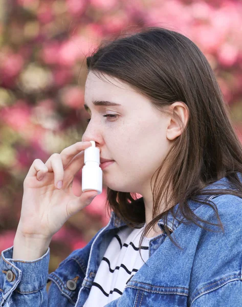 Teenager female  with pollen alergy using nose inhaler in park — Stock Photo, Image